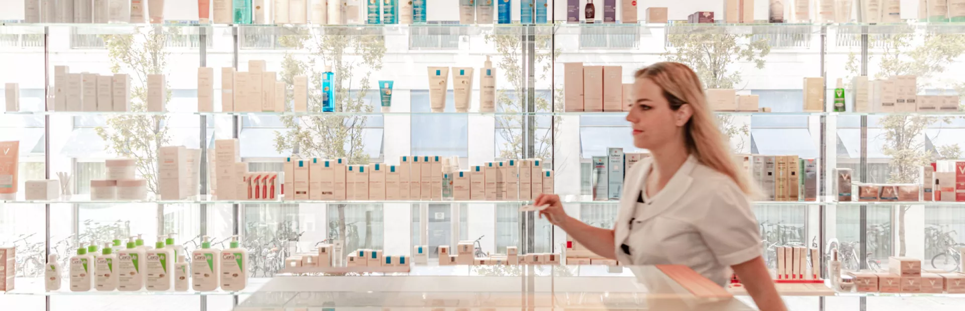 A woman inside a well-stocked and brightly lit pharmacy